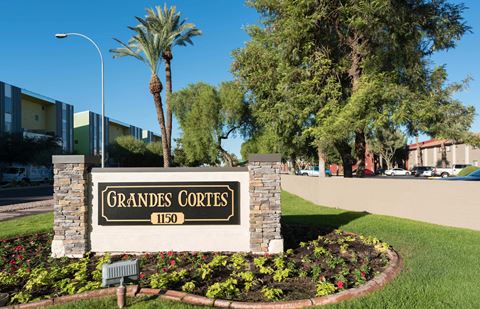 a sign for grande condos in front of a street with palm trees