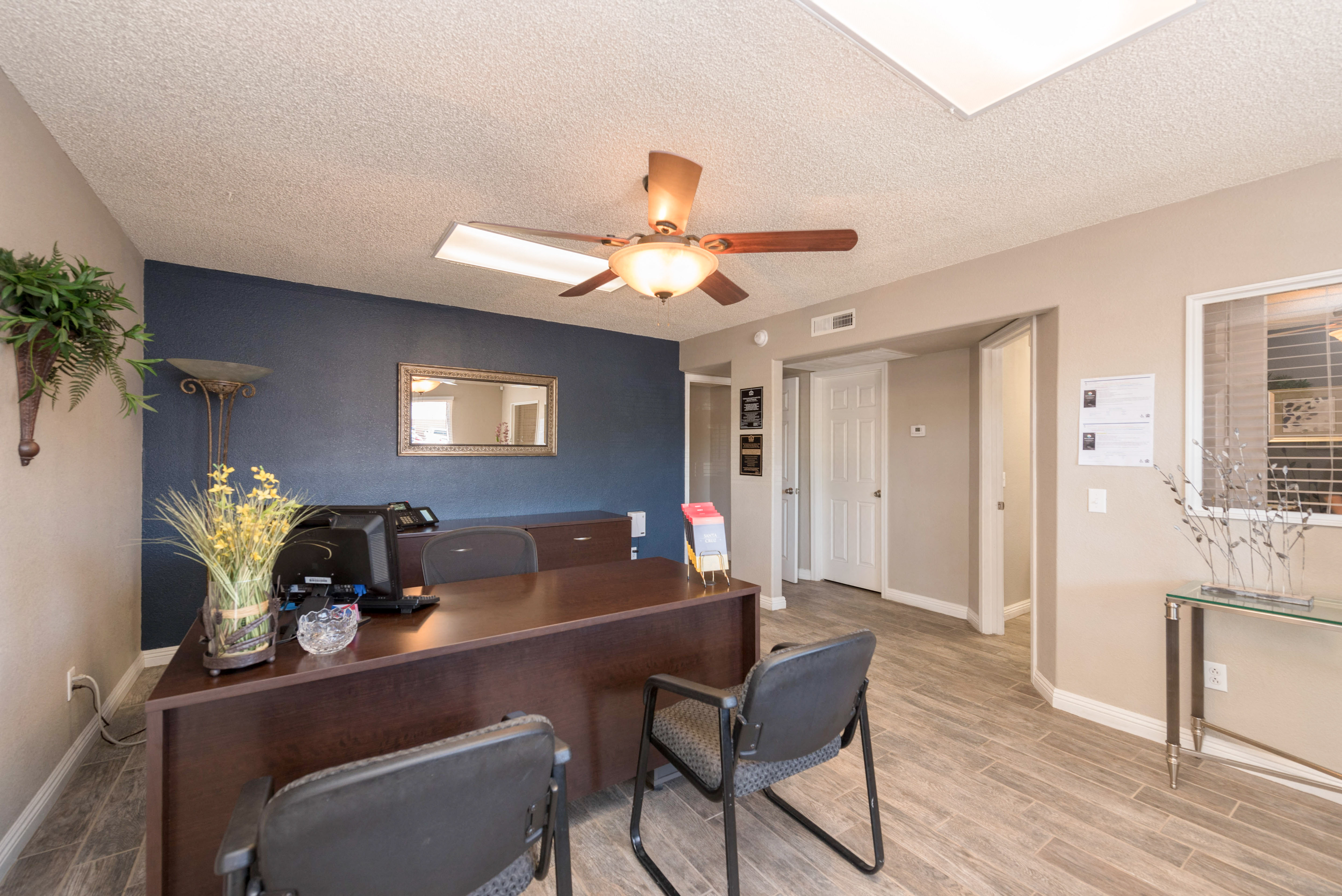 a living room with a desk and a ceiling fan