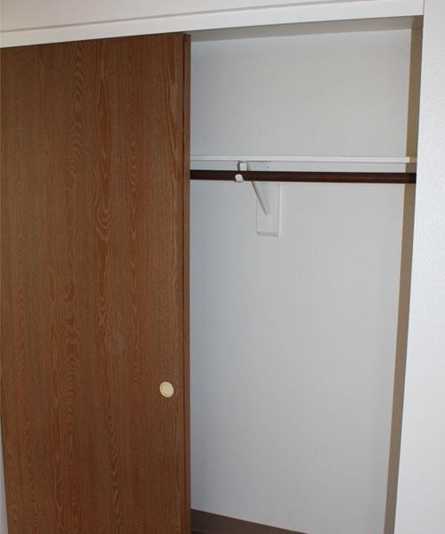 a closet with a white door and a white refrigerator