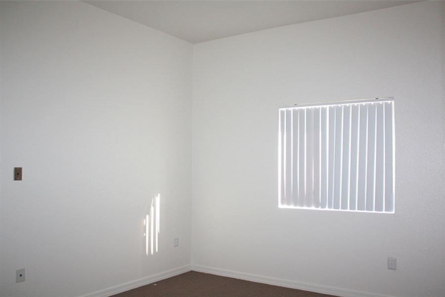 an empty room with a window and white walls