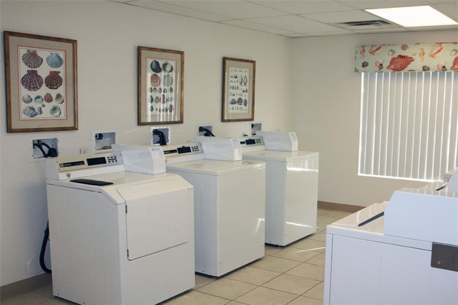 four white washing machines in a room with pictures on the wall