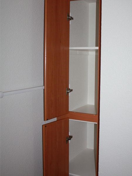 a wooden cabinet with glass shelves in a white room