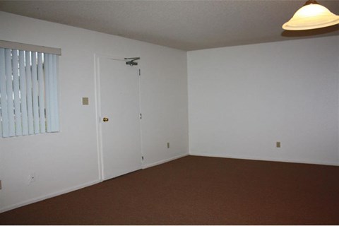 an empty living room with white walls and a window