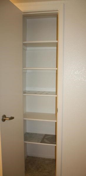 a closet with white shelves and a white door
