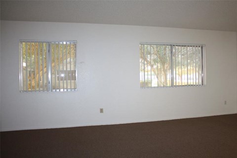 a white room with two windows and a brown carpet