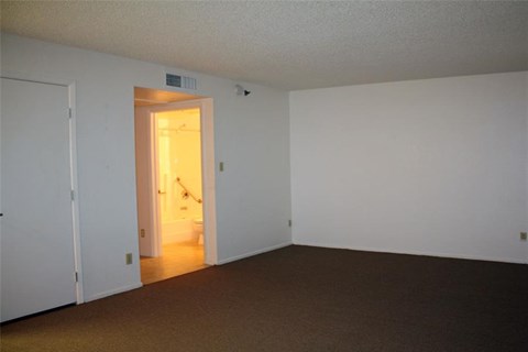 an empty living room with a door to a bathroom