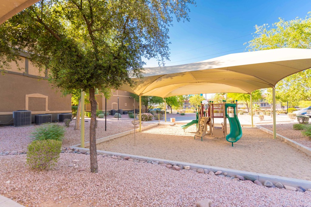 a playground with a slide and trees in a park