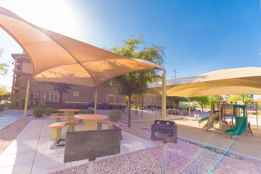 a picnic area with benches and umbrellas at a playground