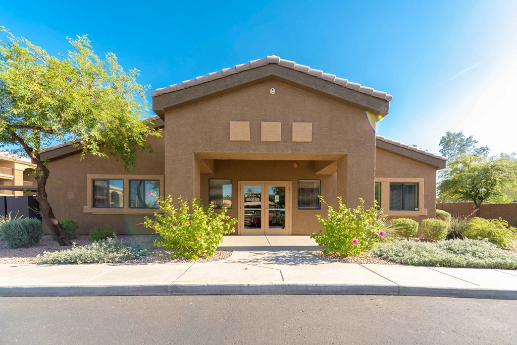 the front of a brown house with a sidewalk and trees
