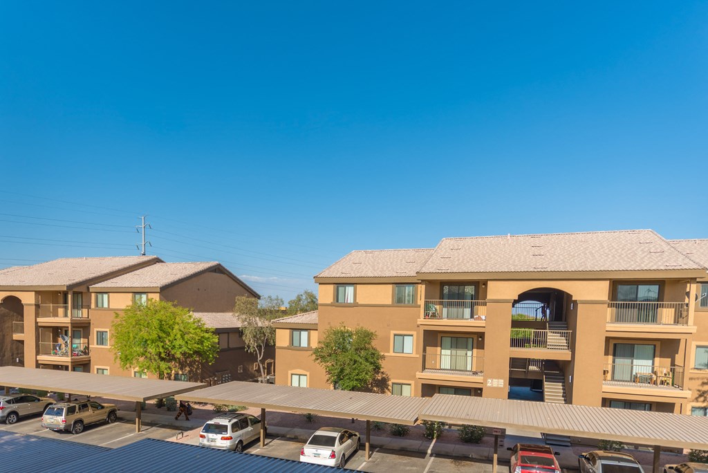 a view of an apartment complex with cars parked in a parking lot