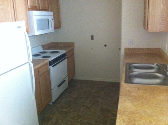 an empty kitchen with a stove refrigerator and sink