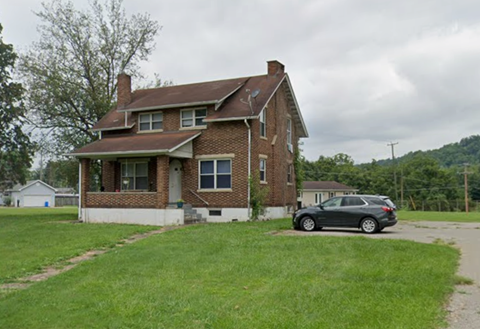 A brick house with a car parked in front.