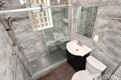 A bathroom with a glass shower door and a toilet.