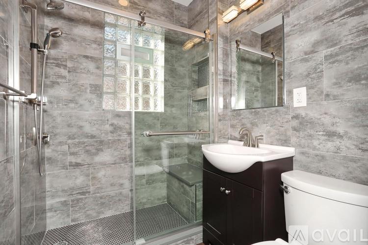 A bathroom with a glass shower stall and a white sink.