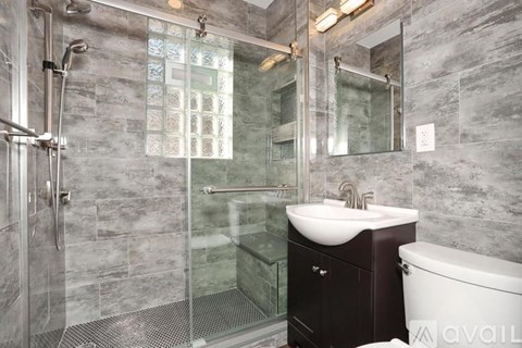 A bathroom with a glass shower stall and a white sink.