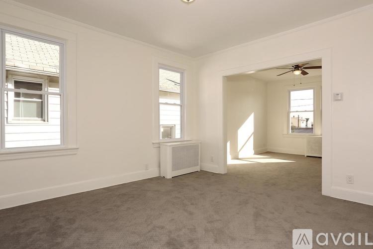 A spacious room with a carpeted floor and a ceiling fan.