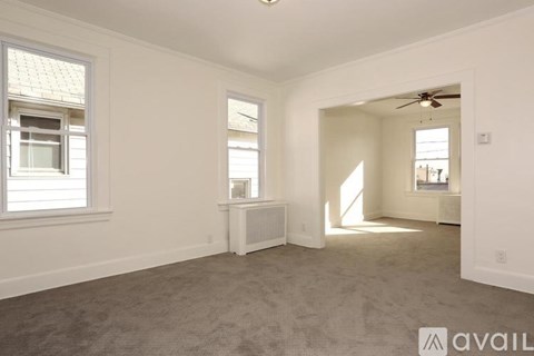 A spacious room with a carpeted floor and a ceiling fan.
