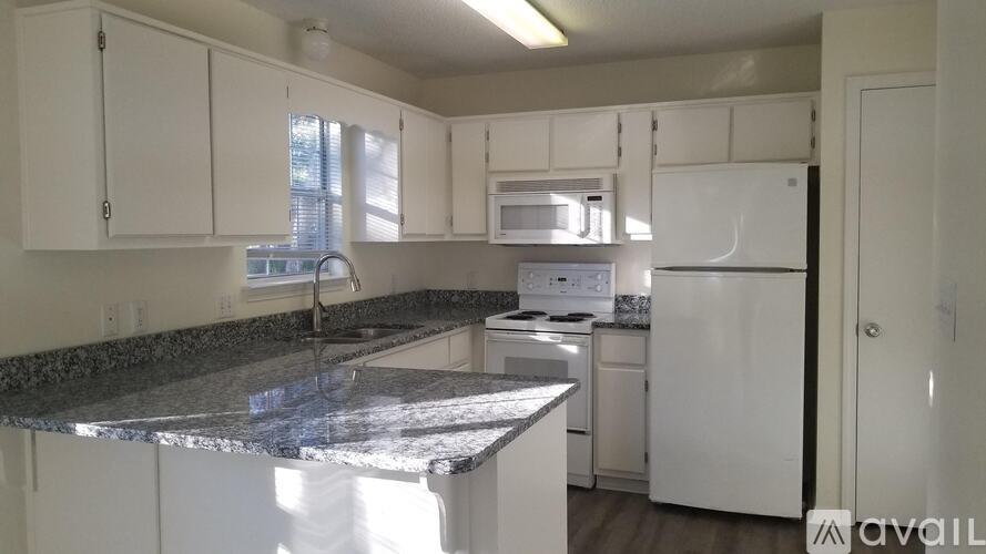A kitchen with granite countertops and white appliances.