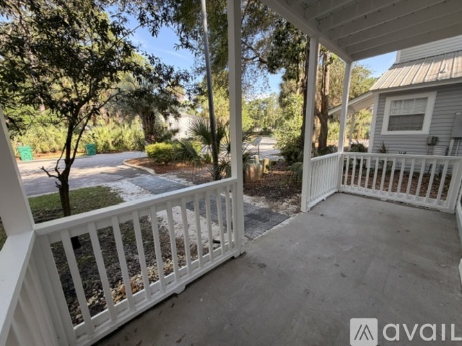 A white porch with a view of a street and trees.