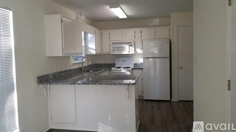 A kitchen with white cabinets and a granite countertop.