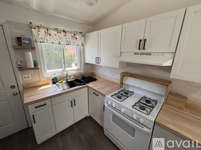 A kitchen with white cabinets and a wooden countertop.