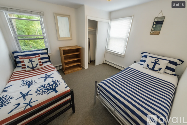 A bedroom with two beds and a wooden bookshelf.