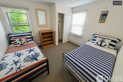 A bedroom with two beds and a wooden bookshelf.