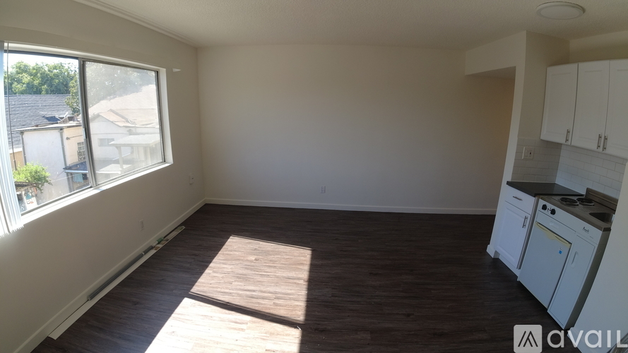 A room with wooden flooring and a window letting in sunlight.