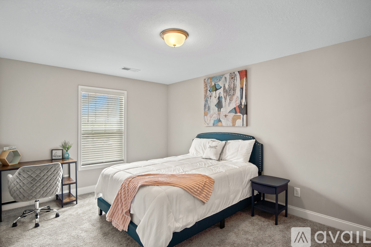 A bedroom with a large bed and a painting on the wall.