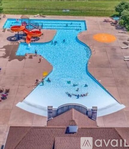 A large outdoor swimming pool with a slide and people enjoying the water.