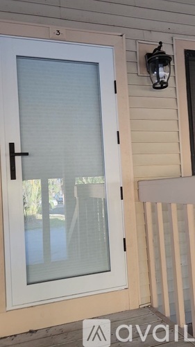 A white door with a black handle and a black lantern on the wall.