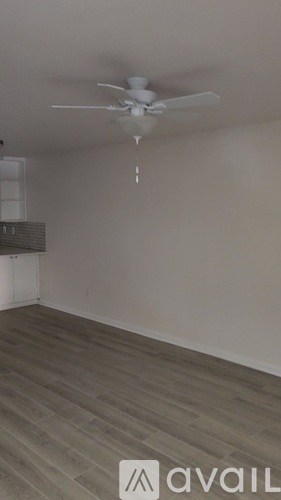 A room with a ceiling fan and wooden flooring.