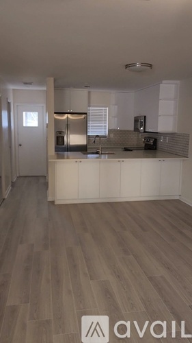 A kitchen with white cabinets and a wooden floor.