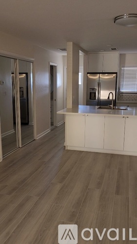 A kitchen with a white counter and wooden flooring.