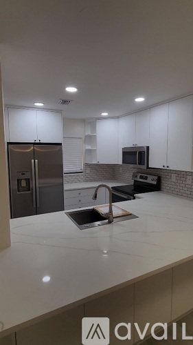 A modern kitchen with a refrigerator, microwave, and sink.