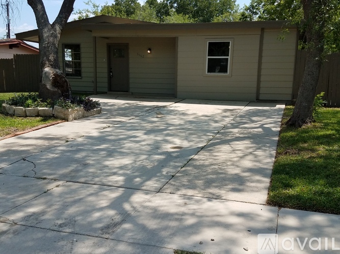 A house with a driveway and a tree in front.