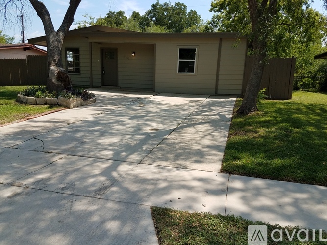 A house with a driveway and a tree in front.