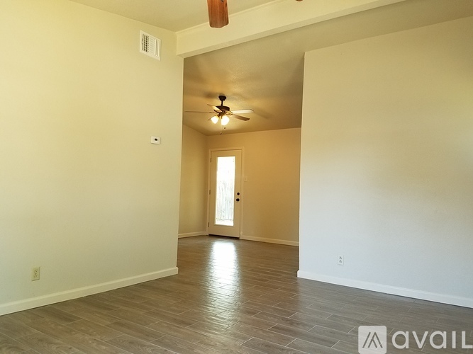 A spacious room with a ceiling fan and a door leading to another room.