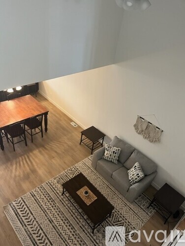 A living room with a grey sofa and a patterned rug.