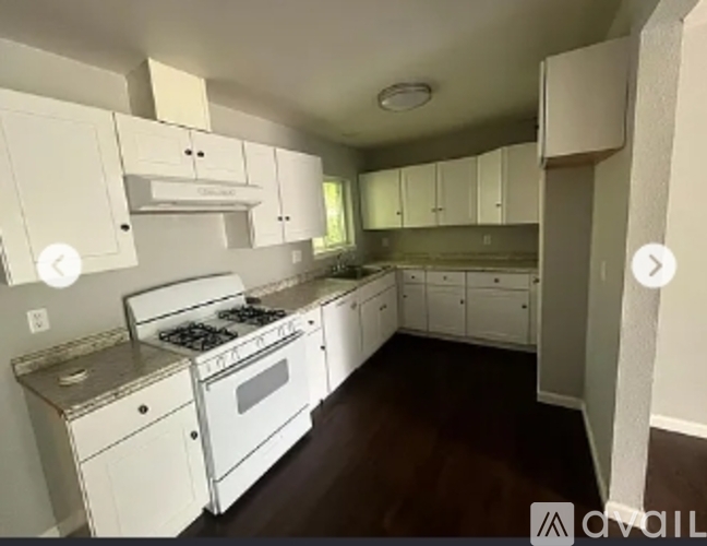 A kitchen with white cabinets and a stove top oven.