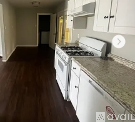 A kitchen with a stove top oven and white cabinets.