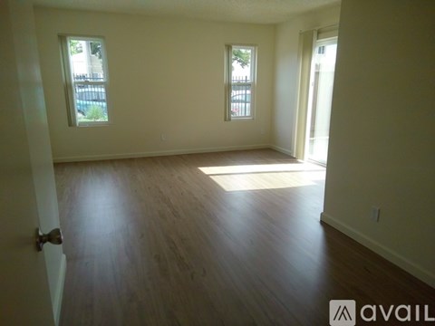 A room with wooden floors and two windows.