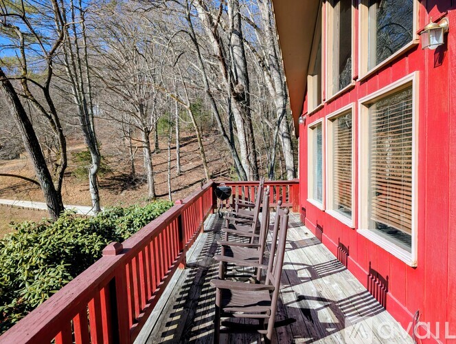 A red building with a balcony and wooden chairs.