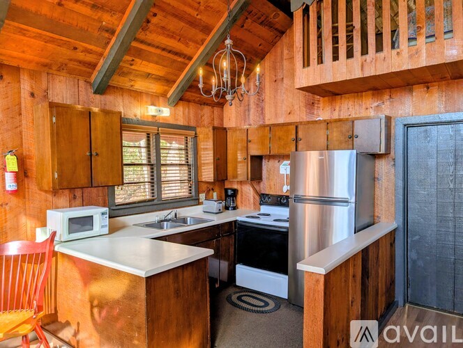 A kitchen with wooden walls and a stainless steel refrigerator.