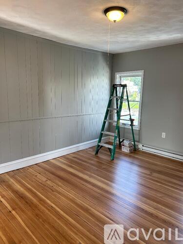 A room with wooden flooring and a ladder against the wall.