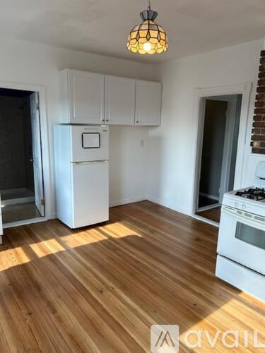 A kitchen with white appliances and wooden floors.