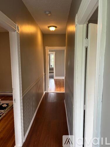 A long hallway with white walls and wood floors.