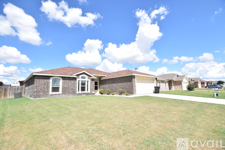 A house with a brown roof and a white fence is for sale.