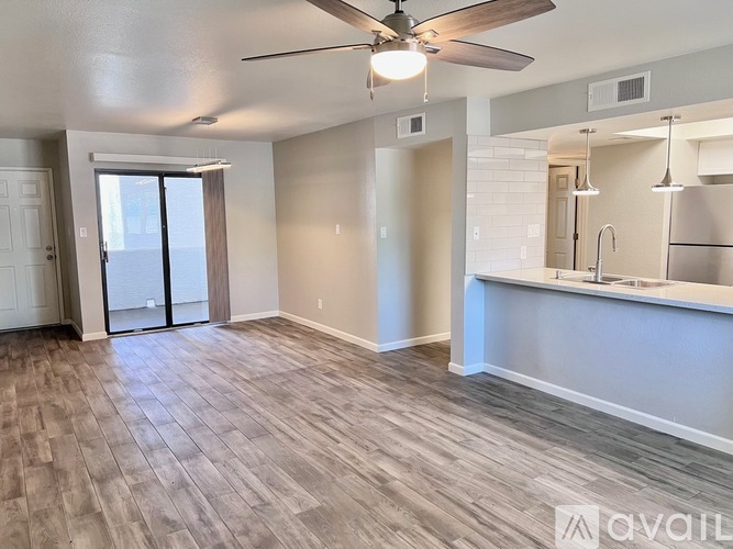 A spacious room with a ceiling fan and wooden flooring.