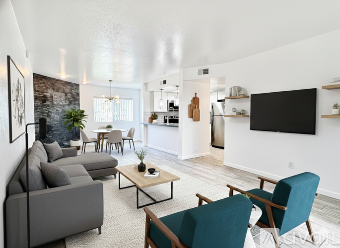 A living room with a grey couch, a coffee table, and a flat screen TV mounted on the wall.